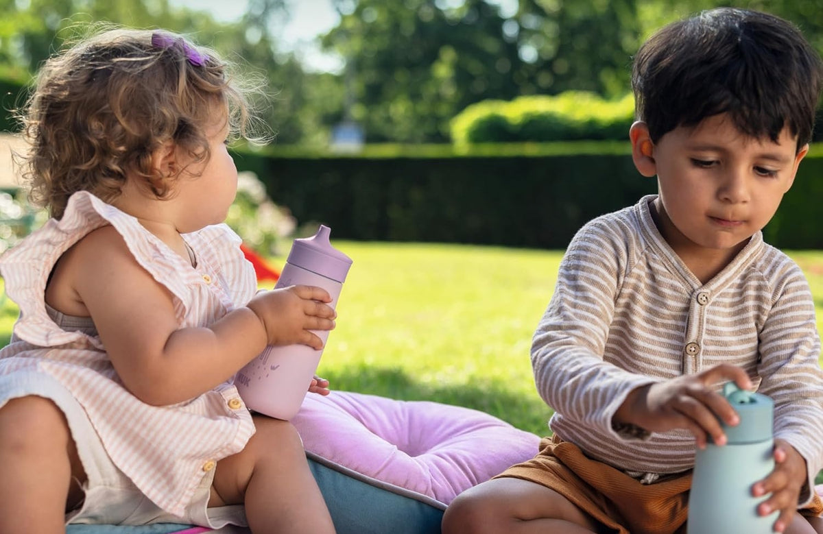 Dzieci trzymające beżową butelkę NUK Mini-Me Sip z motywem lisa.
