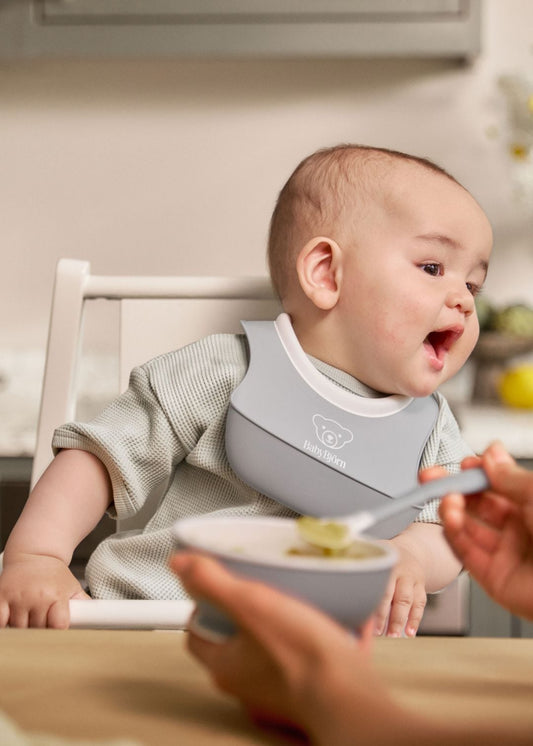 Zdjęcie poglądowe opiekuna podającego posiłek dziecku łyżeczką BabyBjörn.